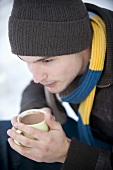 Junger Mann trinkt heissen Kakao