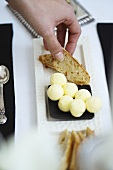 Hand greift nach Brotscheibe und Butter