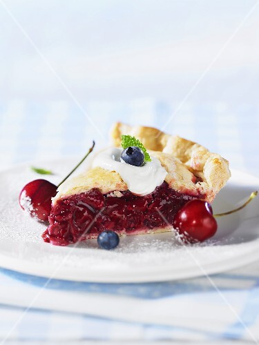 A piece of cherry pie with fresh cherry and blueberries