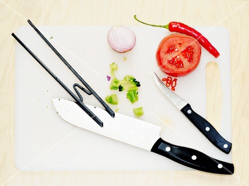 Chopped vegetables on a chopping board with knives