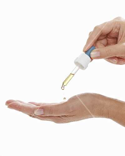 Flüssigkeit mit Pipette in die Handfläche tropfen