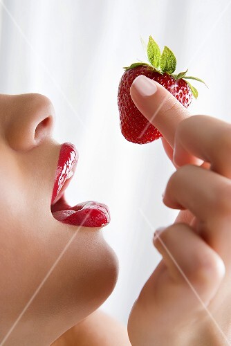 A woman holding a strawberry