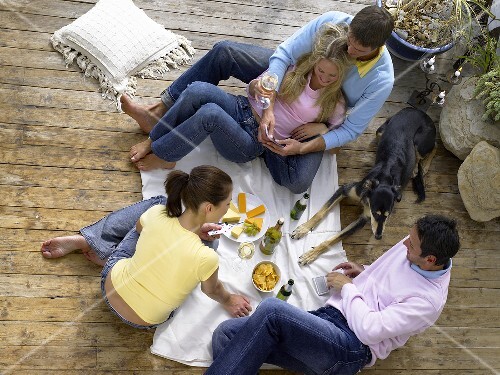 Friends sitting on the floor having drinks and playing cards