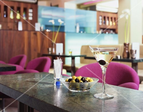 Martini in cocktail glass and dish of olives