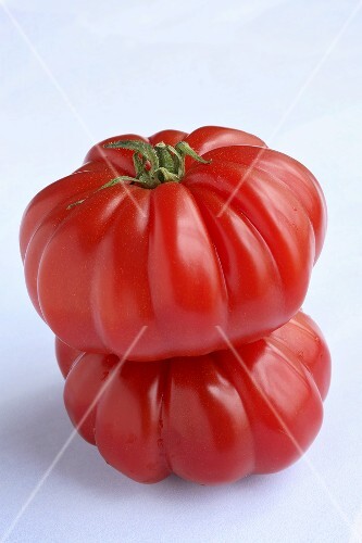 Two 'Coeur de Boeuf' beefsteak tomatoes, one on top of the other
