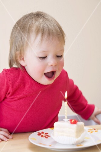 Kleines Mädchen bläst Geburtstagskerze aus