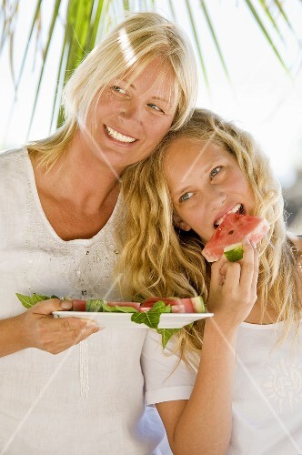 Mutter und Tochter essen Wassermelone im Freien