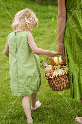 Little girl carrying a picnic basket with her mother
