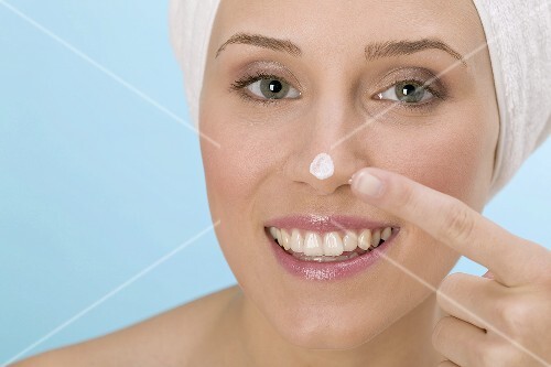 Woman dabbing face cream on her nose