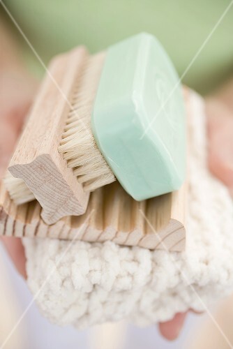 Woman holding soap, soap dish, brush and towel