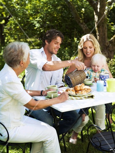 Family drinking coffee in the garden in summer