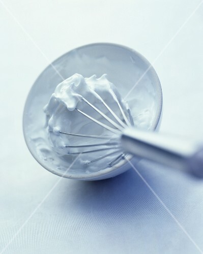 Beaten egg white in bowl with whisk