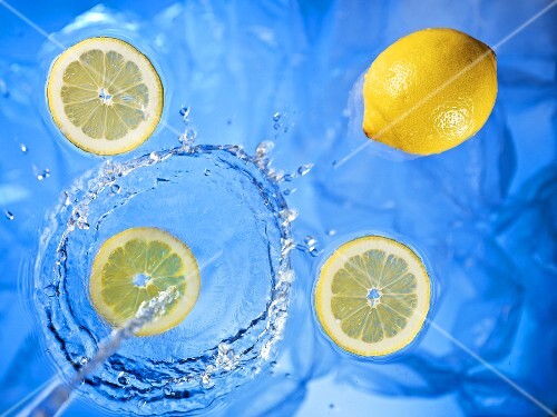 Stream of water running onto lemons and lemon slices