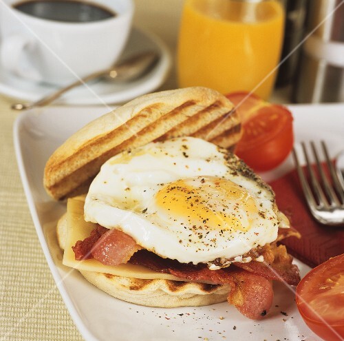 Fried egg, bacon, cheese & tomatoes on bread roll for breakfast