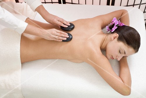 Young woman receiving hot stone massage, elevated view