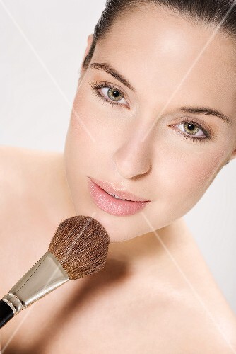 Young woman using make up brush, portrait