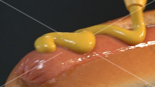 Putting mustard on a hot dog