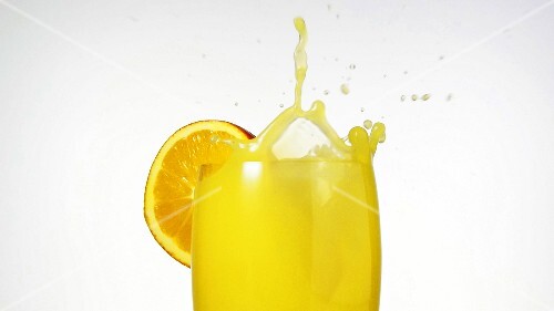 Ice cube falling into a glass of orange juice