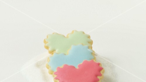Heart-shaped biscuits with coloured icing on heap of sugar