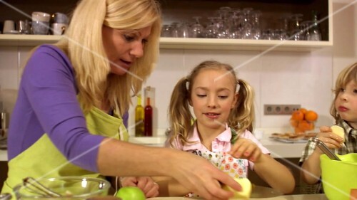 Vater mit Laptop, Mutter und Kinder beim Kuchen backen