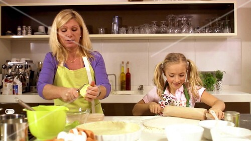 Mother and daughter baking apple tart together