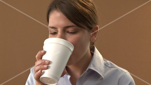 Young woman drinking coffee out of a paper cup