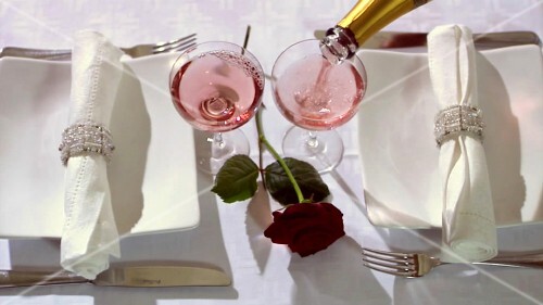 Elegantly laid table with red rose and rosé wine