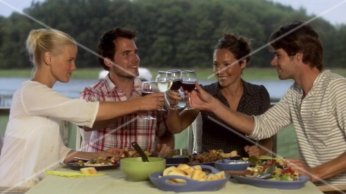 Four friends having evening meal together out of doors