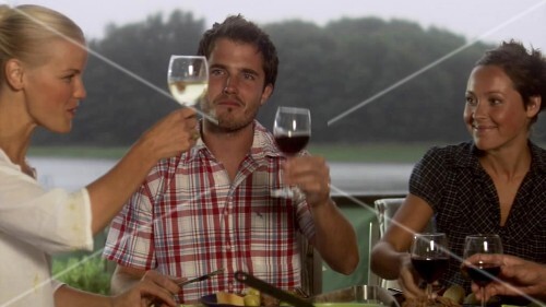 Four friends having evening meal together out of doors