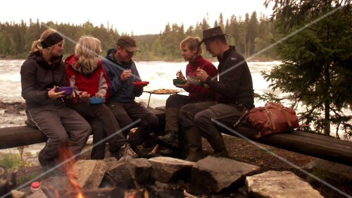 Friends sitting eating by fire