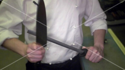 Chef sharpening a kitchen knife with a sharpening steel