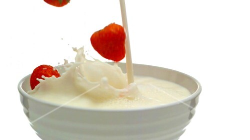 Milch und Erdbeeren in eine Schale geben (Close Up)