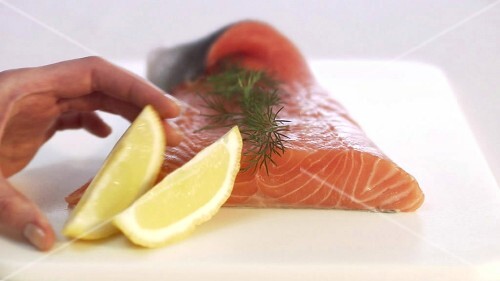 Garnishing gravlax with lemon (close-up)