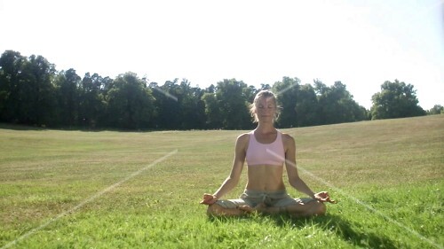 Woman in lotus position in a pasture