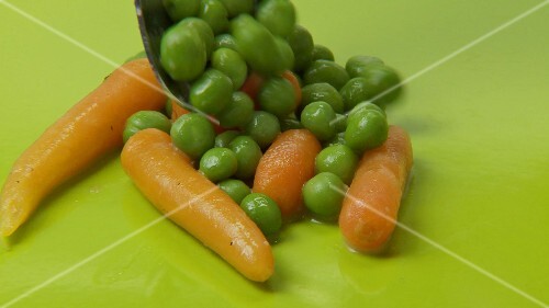 Carrots and peas with butter curls on green background