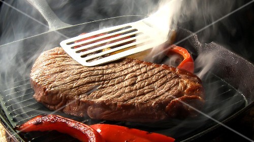 Strips of red pepper and steak in a grill frying pan