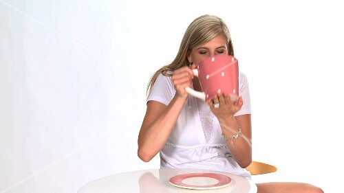 Blond woman drinking out of a giant cup