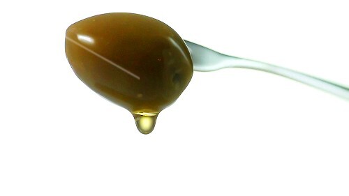 Olive oil dripping from green olive