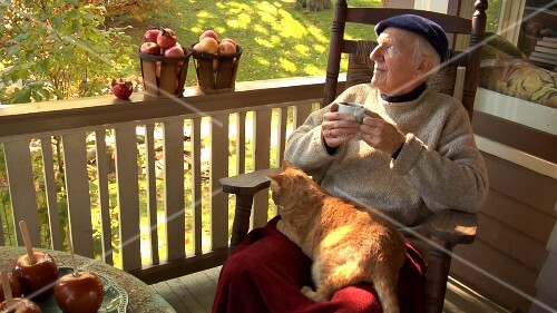 Elderly man sitting on balcony drinking apple punch