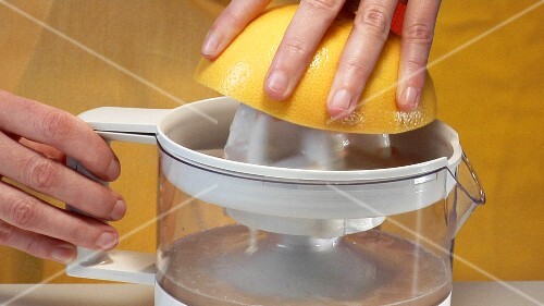 Squeezing pink grapefruit with electric citrus squeezer