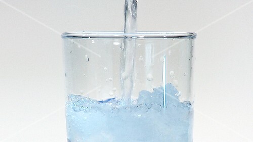 Pouring water into a glass of crushed ice (close-up)