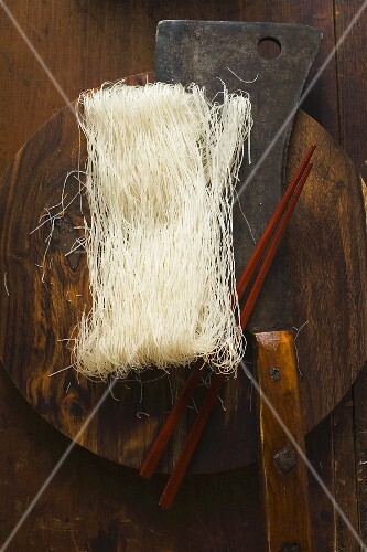 Thin rice noodles on wooden plate with Asian cleaver