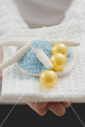 Young woman holding bath salts & bath pearls with starfish
