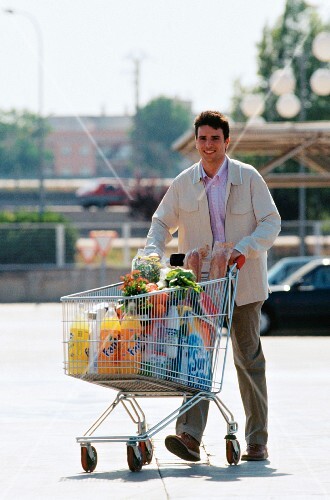 Man food shopping in car park with shopping trolley