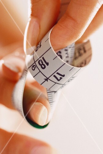 Tape measure coiled between fingers (close-up)