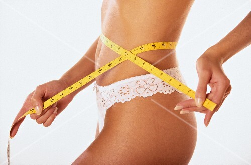 Woman measuring waist with tape measure