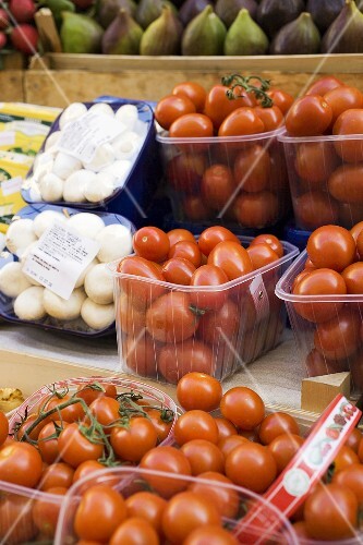 Tomatoes and mushrooms in plastic punnets at a market