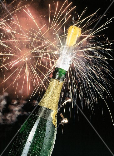 Korken springt aus Sektflasche, Hintergrund: Feuerwerk