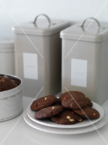 Chocolate biscuits with peanuts and storage tins in the background