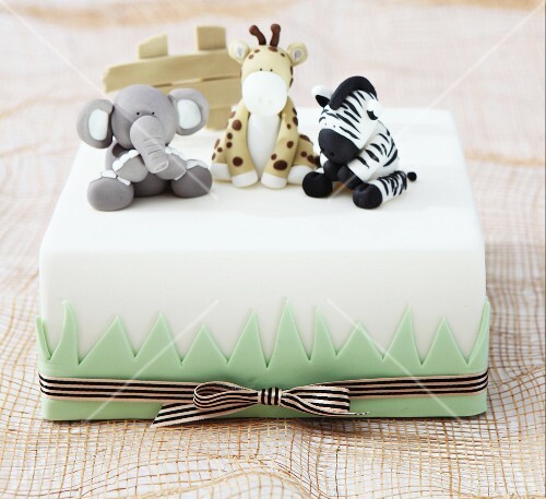 A white cake decorated with animals made from fondant icing